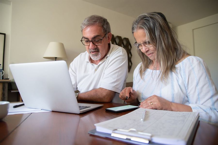 Couple at a desk planning a trip together on a laptop